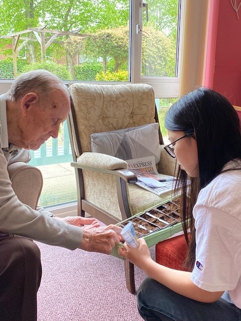 A resident at Corton House plants a sunflower seed in a tray held by a volunteer