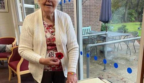 Norwich care home resident Norma with a pile of knitted poppy brooches sold to raise money for charity.